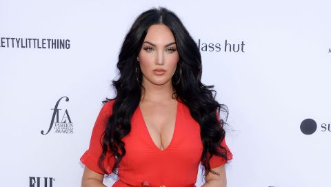 Natalie Halcro in a red dress poses a picture.